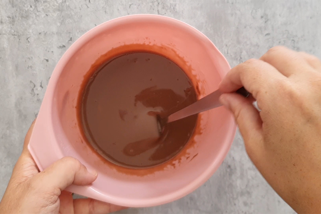 Kinder fondu au micro-ondes dans un bol rose, mélangé à la spatule