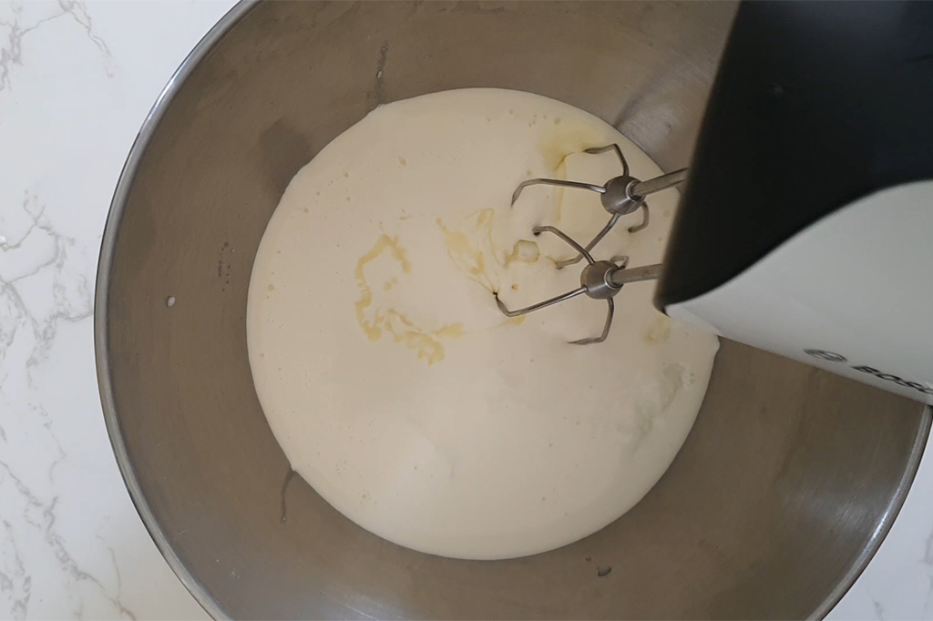 Battre le yaourt, la crème et le lait concentré sucré au batteur électrique
