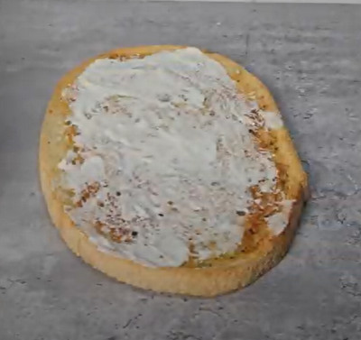 Tartines de bruschetta garnies de crème fraîche, mozzarella et rondelles de chèvre avant cuisson