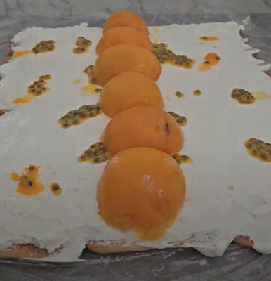 Gâteau roulé aux pêches et à la passion sans cuisson, décoré de crème